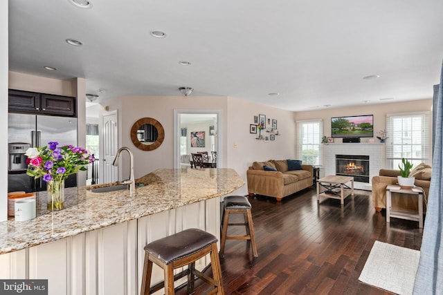 5229 Woodleaf Ct, Centreville, VA 20120 - kitchen featuring stainless steel refrigerator with ice dispenser, a sink, dark wood-style floors, a kitchen breakfast bar, and light stone countertops