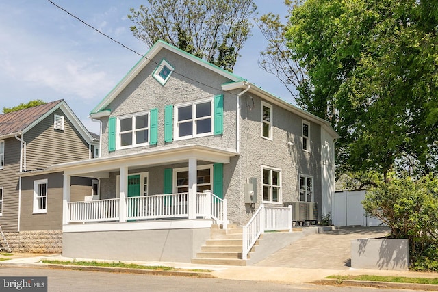 view of front of house with fence, stucco siding, and a porch