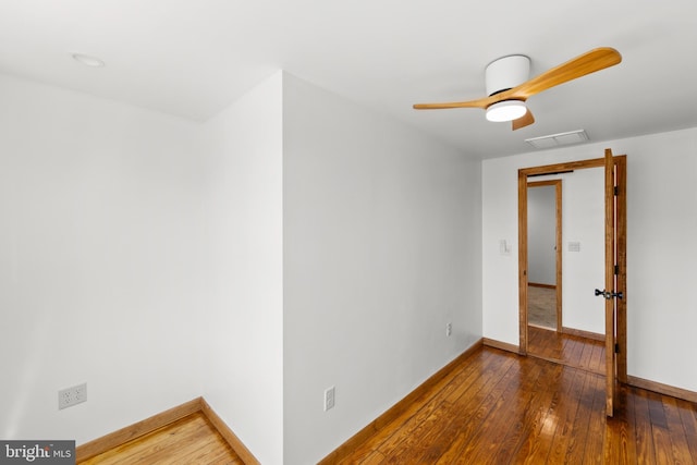spare room featuring visible vents, attic access, baseboards, and hardwood / wood-style flooring