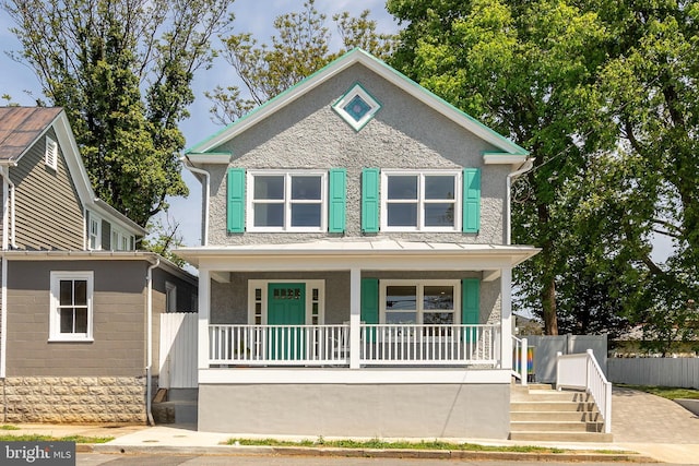 view of front of home with fence, stucco siding, and a porch