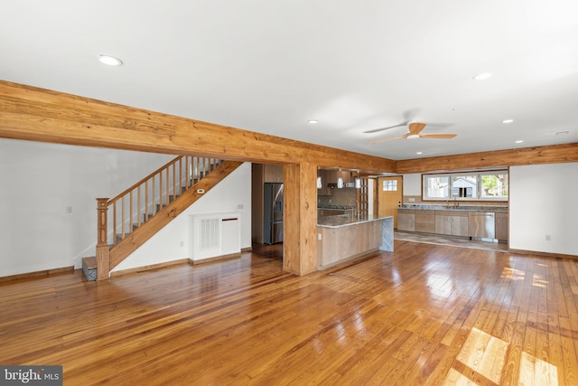 unfurnished living room with ceiling fan, stairs, a sink, recessed lighting, and light wood-style flooring