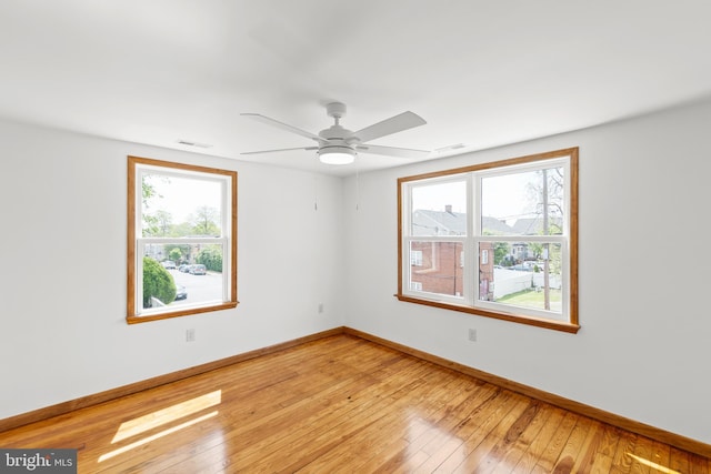 spare room featuring visible vents, light wood-style flooring, ceiling fan, and baseboards