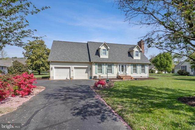 new england style home with an attached garage, driveway, a front yard, and a chimney