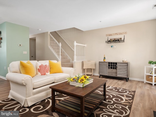 living room with baseboards, stairs, wood finished floors, and visible vents