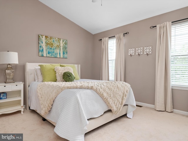 bedroom featuring multiple windows, light colored carpet, and lofted ceiling
