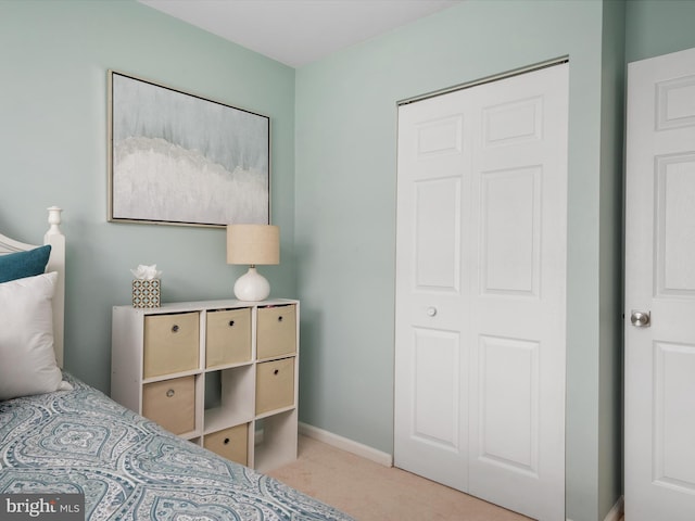 carpeted bedroom featuring baseboards and a closet