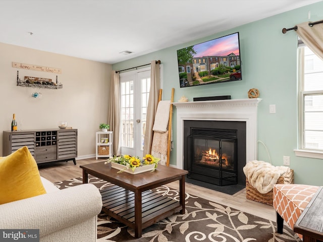 living room with visible vents, a fireplace with flush hearth, and wood finished floors