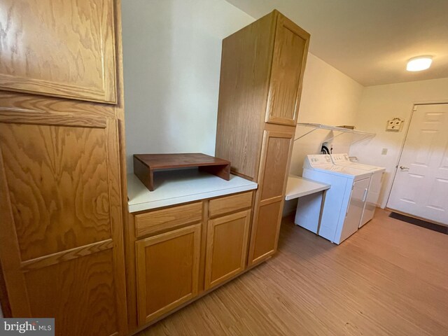 washroom featuring laundry area, washing machine and dryer, and light wood finished floors