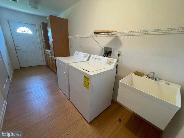 washroom with independent washer and dryer, laundry area, a sink, and light wood-style floors