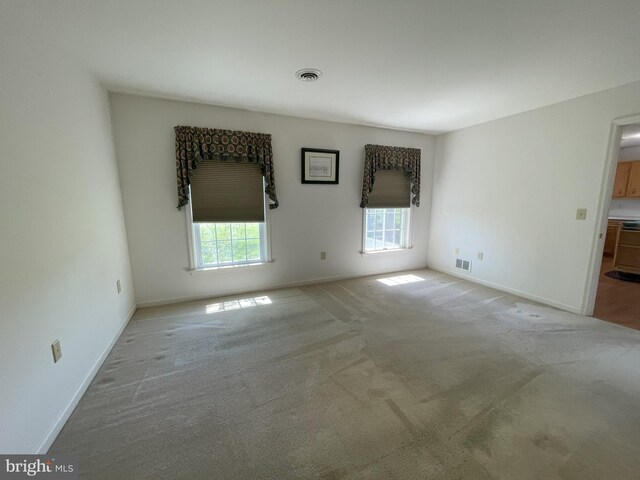 empty room featuring light colored carpet, baseboards, and visible vents