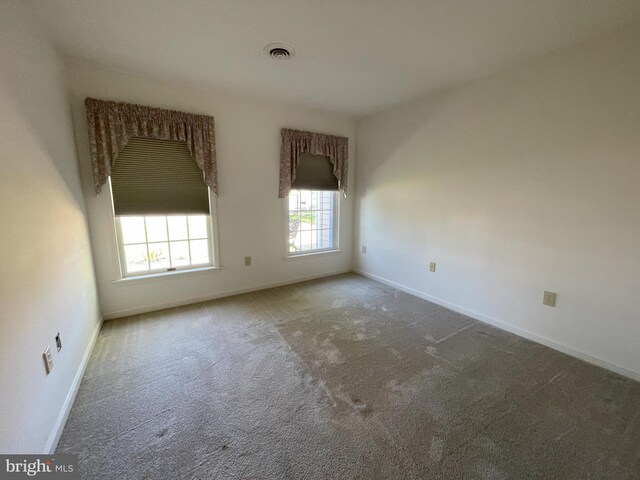 spare room with baseboards, carpet, and visible vents