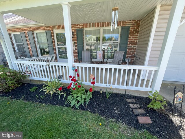 property entrance featuring a porch, brick siding, and an attached garage