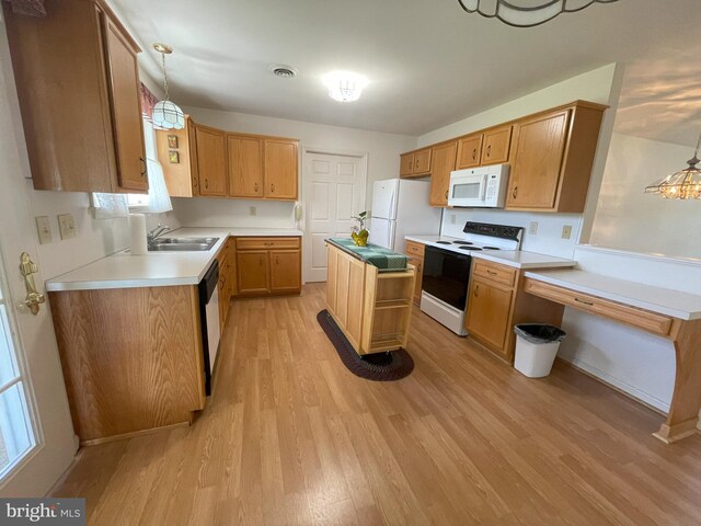 kitchen featuring visible vents, pendant lighting, light wood-type flooring, a sink, and white appliances