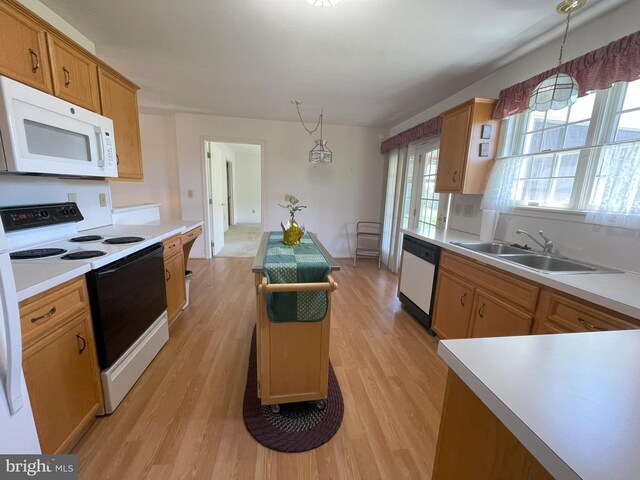 kitchen featuring a sink, pendant lighting, white appliances, and light wood-style flooring