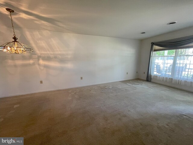 spare room with baseboards, carpet flooring, and a chandelier