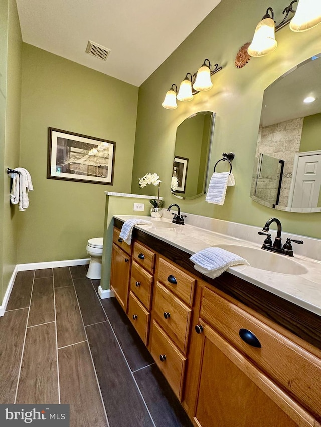 full bathroom featuring a sink, toilet, double vanity, and visible vents