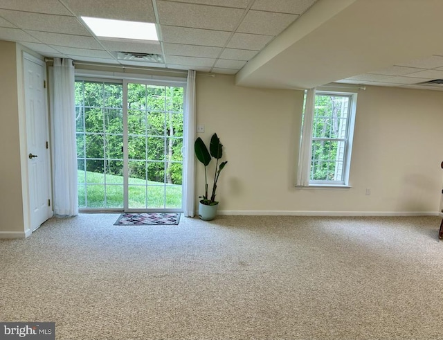carpeted empty room featuring a paneled ceiling, baseboards, and visible vents