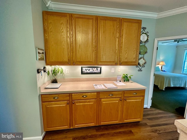 kitchen with dark wood-type flooring, ornamental molding, brown cabinetry, and light countertops