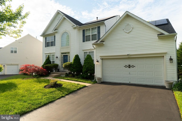 view of front of property featuring driveway, a front yard, and solar panels