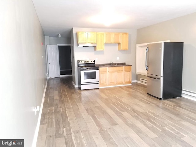 kitchen with light wood-type flooring, light brown cabinets, dark countertops, and stainless steel appliances