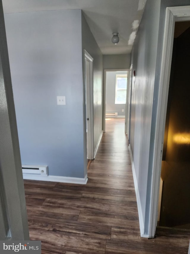 hall featuring baseboards, baseboard heating, and dark wood-style flooring