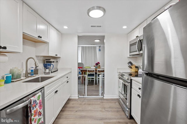 1653 Forest Park, District Heights, MD 20747 - kitchen with light wood-style floors, light countertops, white cabinets, a sink, and appliances with stainless steel finishes