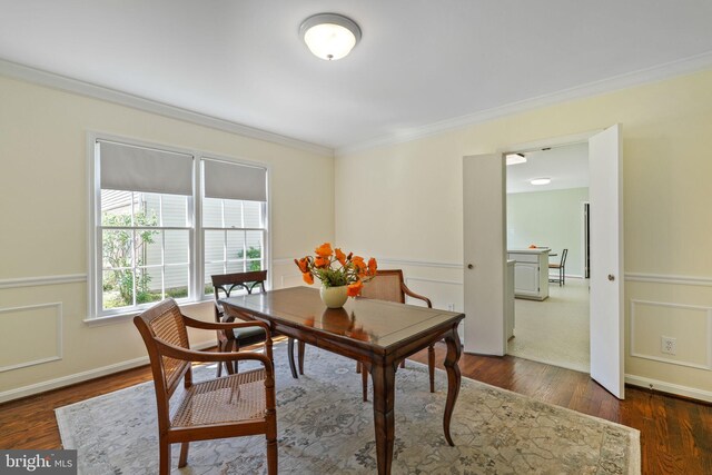 dining space with ornamental molding, a wainscoted wall, and dark wood-type flooring