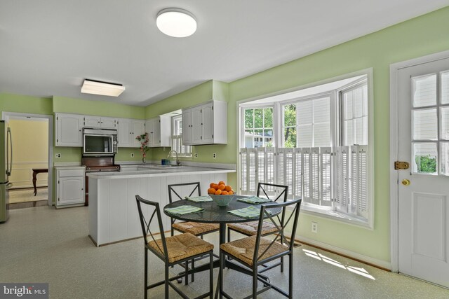 dining area with baseboards, a healthy amount of sunlight, and light floors