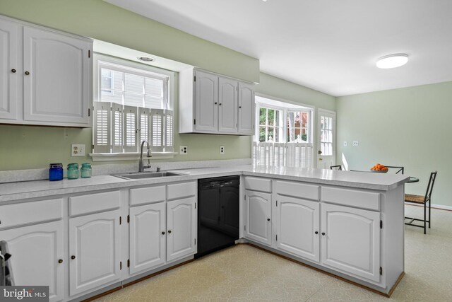 kitchen featuring a peninsula, black dishwasher, light countertops, white cabinets, and a sink