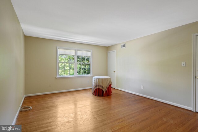 unfurnished room with visible vents, light wood finished floors, and baseboards
