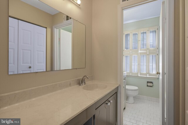 bathroom featuring vanity, baseboards, tile patterned floors, and toilet