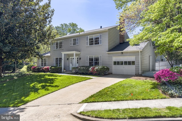 colonial-style house with fence, driveway, a front lawn, and a garage