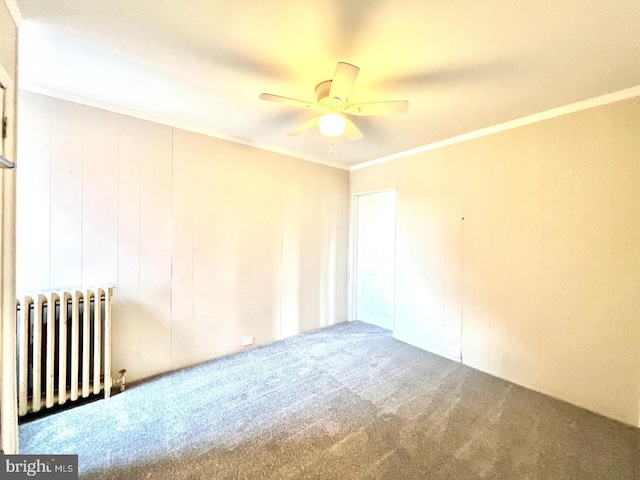 empty room with carpet flooring, radiator, ceiling fan, and ornamental molding
