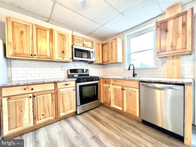 kitchen featuring a sink, appliances with stainless steel finishes, a drop ceiling, and light brown cabinetry
