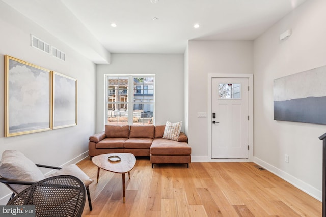 living area with visible vents, light wood finished floors, and baseboards