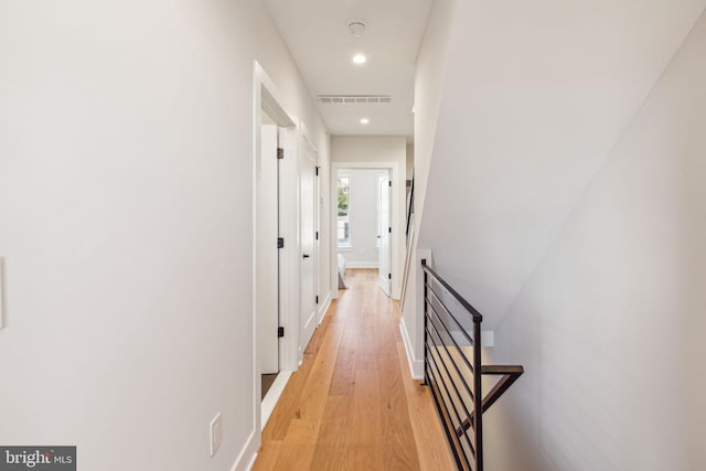 hallway with light wood-style flooring, recessed lighting, baseboards, an upstairs landing, and visible vents