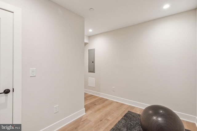 exercise area with baseboards, electric panel, recessed lighting, and light wood finished floors