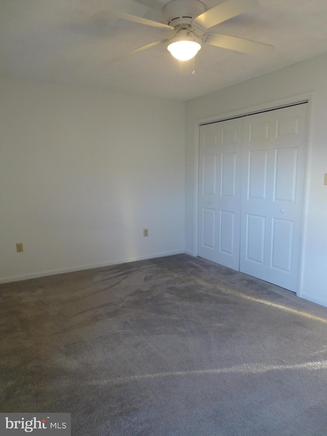 unfurnished bedroom featuring a ceiling fan, baseboards, a closet, and dark colored carpet
