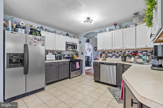 13 Maricopa Trl, Browns Mills, NJ 08015 - kitchen featuring light countertops, white cabinets, tasteful backsplash, arched walkways, and appliances with stainless steel finishes