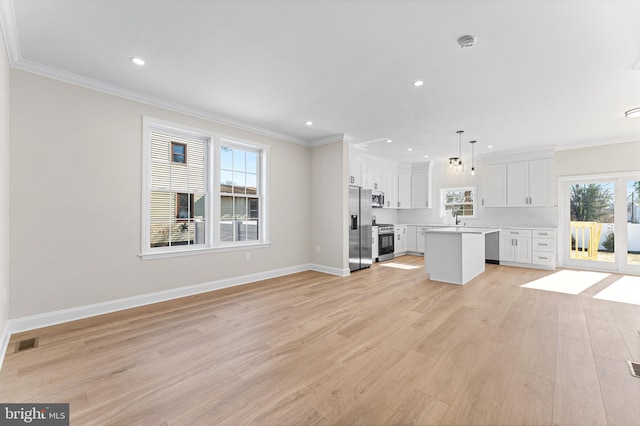 unfurnished living room featuring light wood-style floors, plenty of natural light, ornamental molding, and visible vents