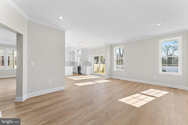 unfurnished living room with crown molding, baseboards, and plenty of natural light