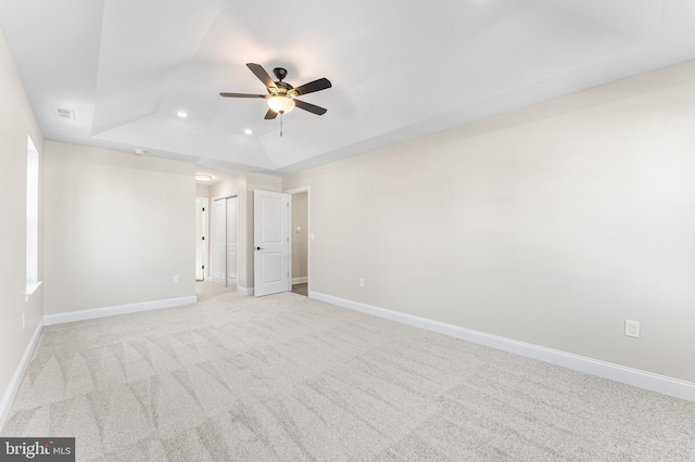 unfurnished bedroom with visible vents, light carpet, baseboards, recessed lighting, and a tray ceiling