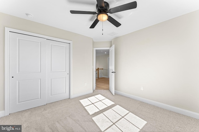 unfurnished bedroom featuring light colored carpet, baseboards, visible vents, and a closet