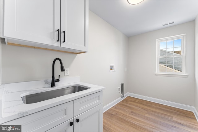 washroom with washer hookup, visible vents, cabinet space, a sink, and baseboards