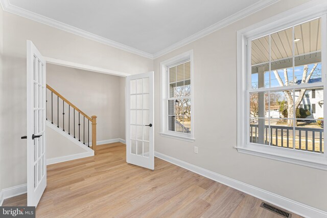 interior space featuring crown molding, visible vents, wood finished floors, baseboards, and french doors