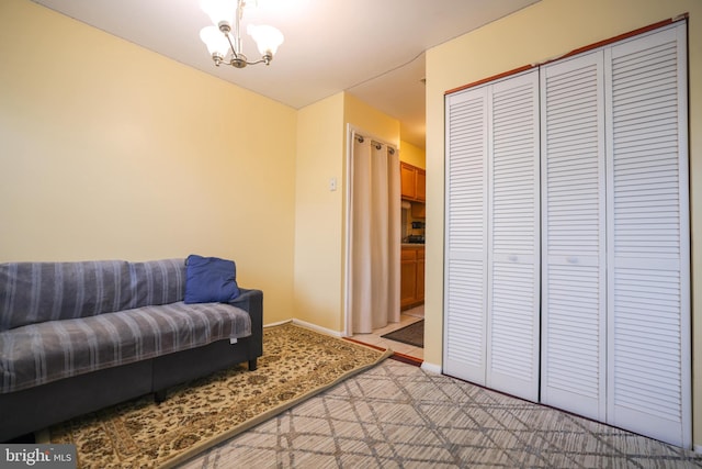 sitting room with baseboards, a notable chandelier, and light carpet