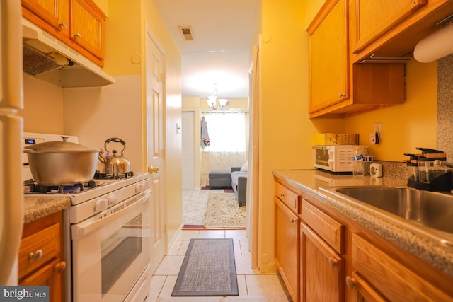 kitchen with visible vents, white gas range, under cabinet range hood, a chandelier, and a sink
