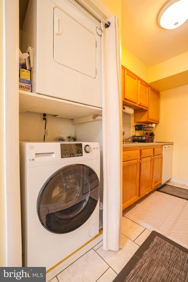 washroom with stacked washing maching and dryer, light tile patterned floors, and laundry area