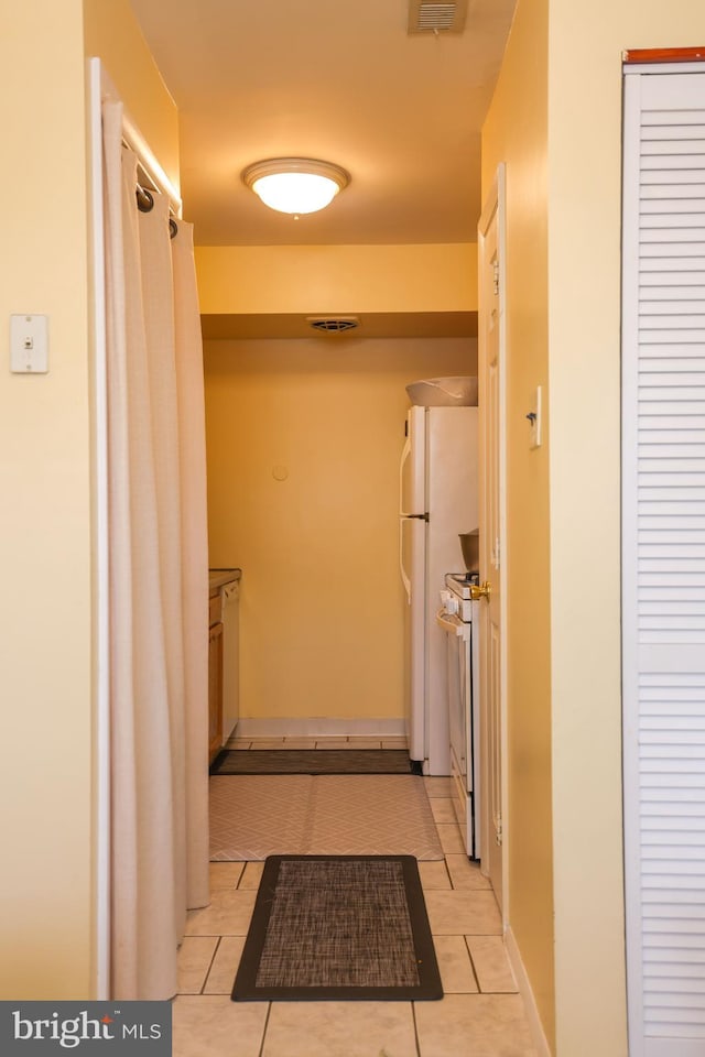 hall featuring light tile patterned flooring and visible vents