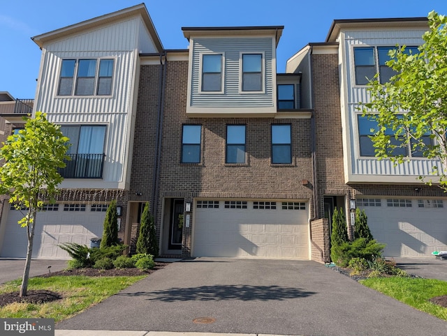 townhome / multi-family property with brick siding, an attached garage, and aphalt driveway